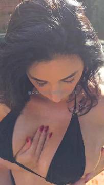 Hot mature brunette rubbing her tits with oil by the pool